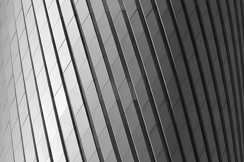 Close-up of a modern building facade with a pattern of vertical and diagonal glass panels reflecting light. Lusail Plaza Tower, Doha, Qatar.