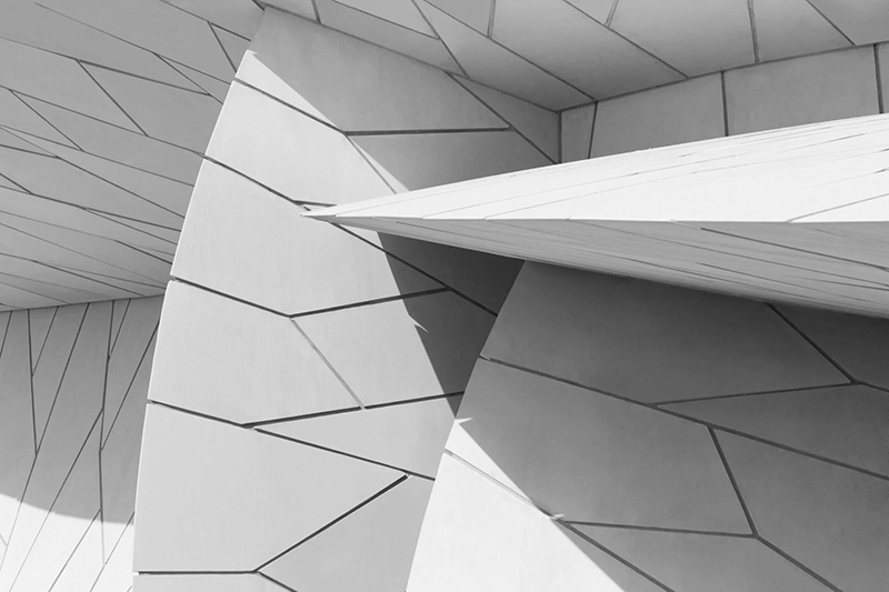 Abstract architectural close-up of interlocking geometric shapes and angled surfaces in monochrome. Qatar National Museum, Doha.