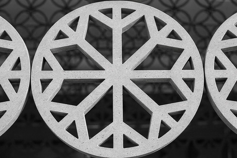 Close-up of a circular decorative concrete panel with geometric triangular and trapezoidal cutouts. Al Rayyan Stadium, Qatar.